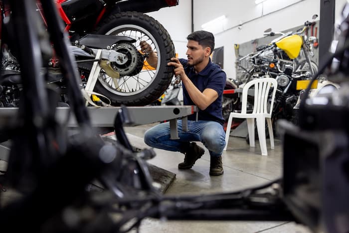 Mechanic installs a wheel on a motorcycle in a repair shop